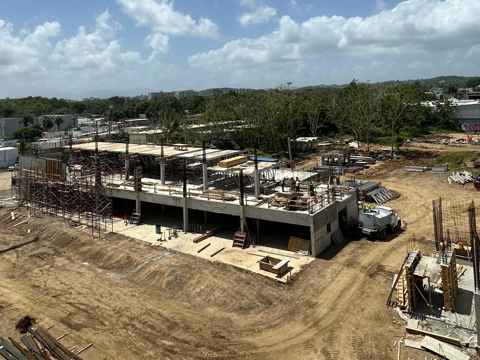 Early-stage Oasis Hub construction with first-floor columns rising and crane on site, June 2025